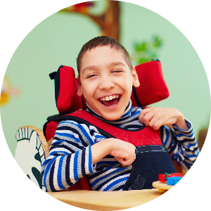 A child in a wheelchair smiles at the camera